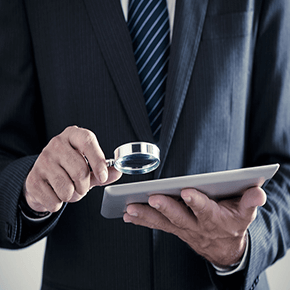 Man using magnifying glass to look at tablet
