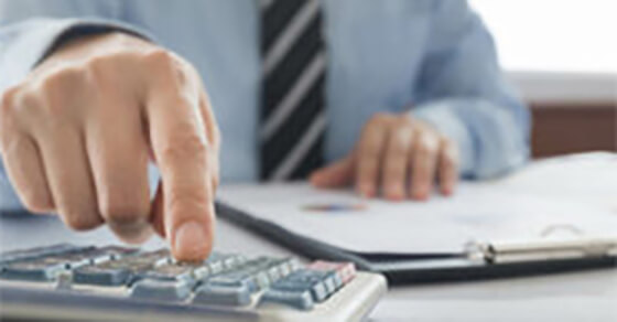 Man typing on calculator while looking at papers