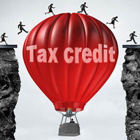 Red hot air balloon with words tax credit between two cliffs with people running over the top